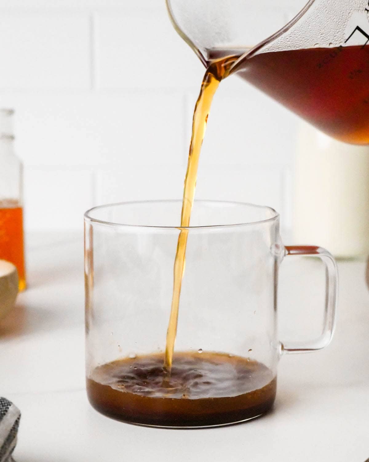 how to make a chai latte - hot brewed tea being poured into a glass mug