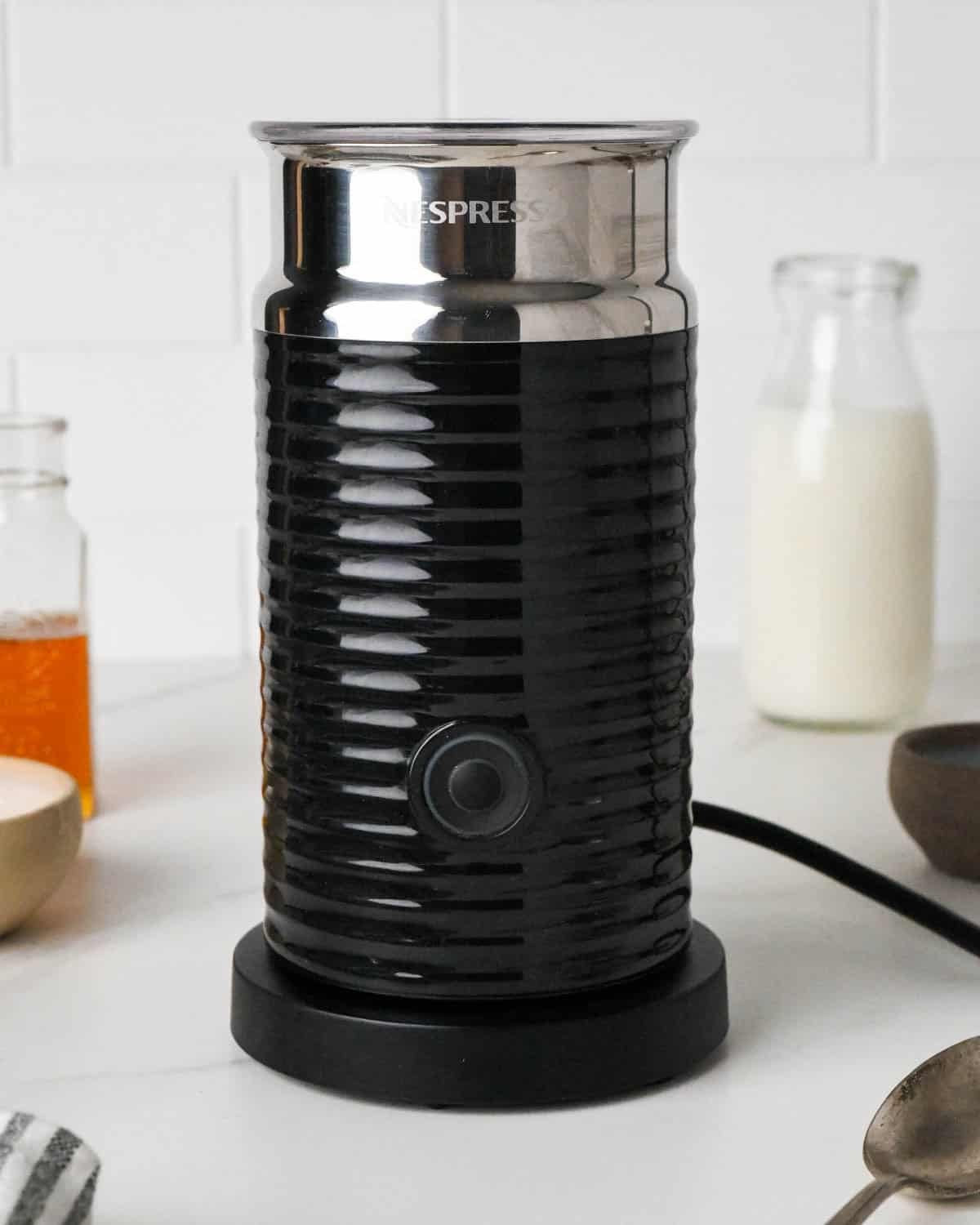 how to make a chai latte - front view of an electric milk frother frothing milk to be used in this recipe