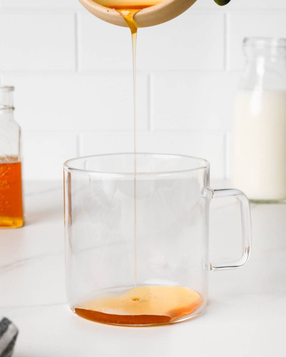 how to make a chai latte -honey being poured into a glass mug