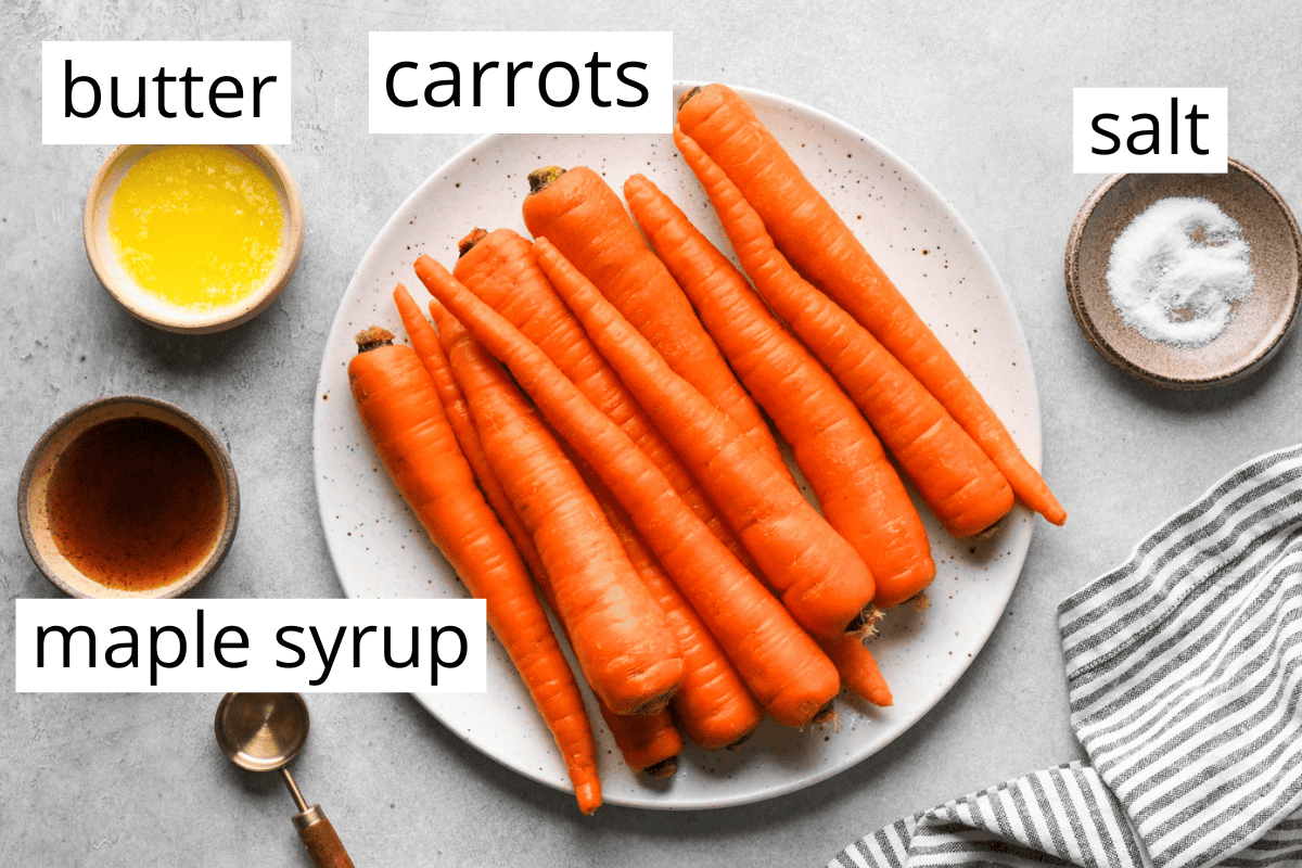 overhead photo of the ingredients in this maple glazed carrots recipe in bowls and labeled. The ingredients are melted butter, whole carrots, salt and maple syrup.