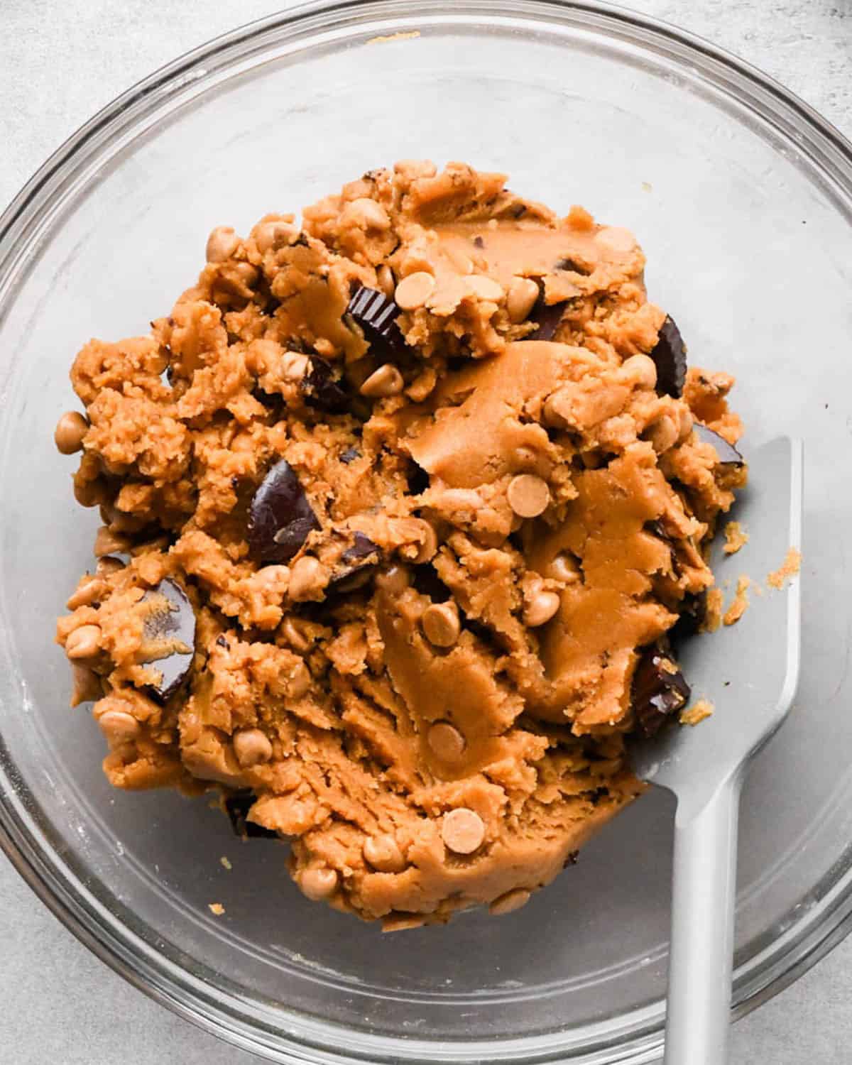 peanut butter blondies dough in a glass bowl with a gray spatula