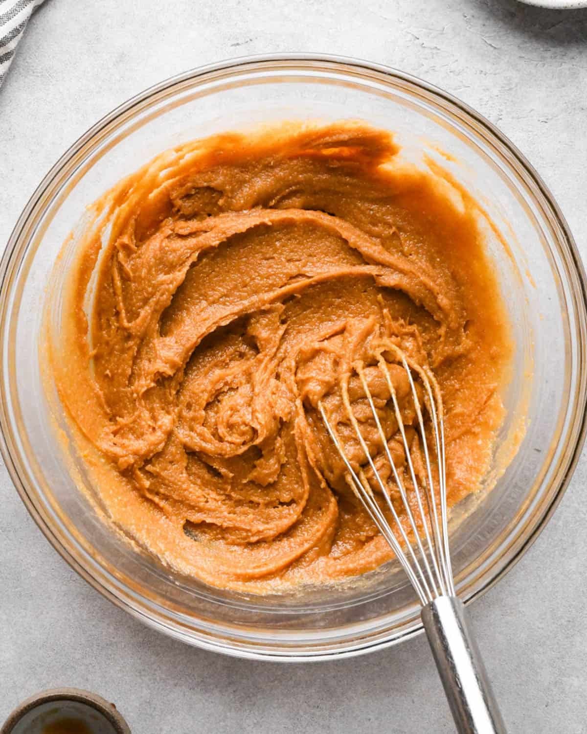 making peanut butter blondies - the batter after whisking in egg and vanilla in a glass mixing bowl with a metal whisk