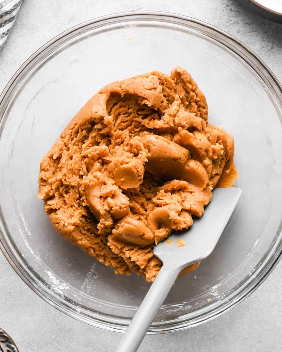 peanut butter blondies dough in a glass bowl with a gray spatula