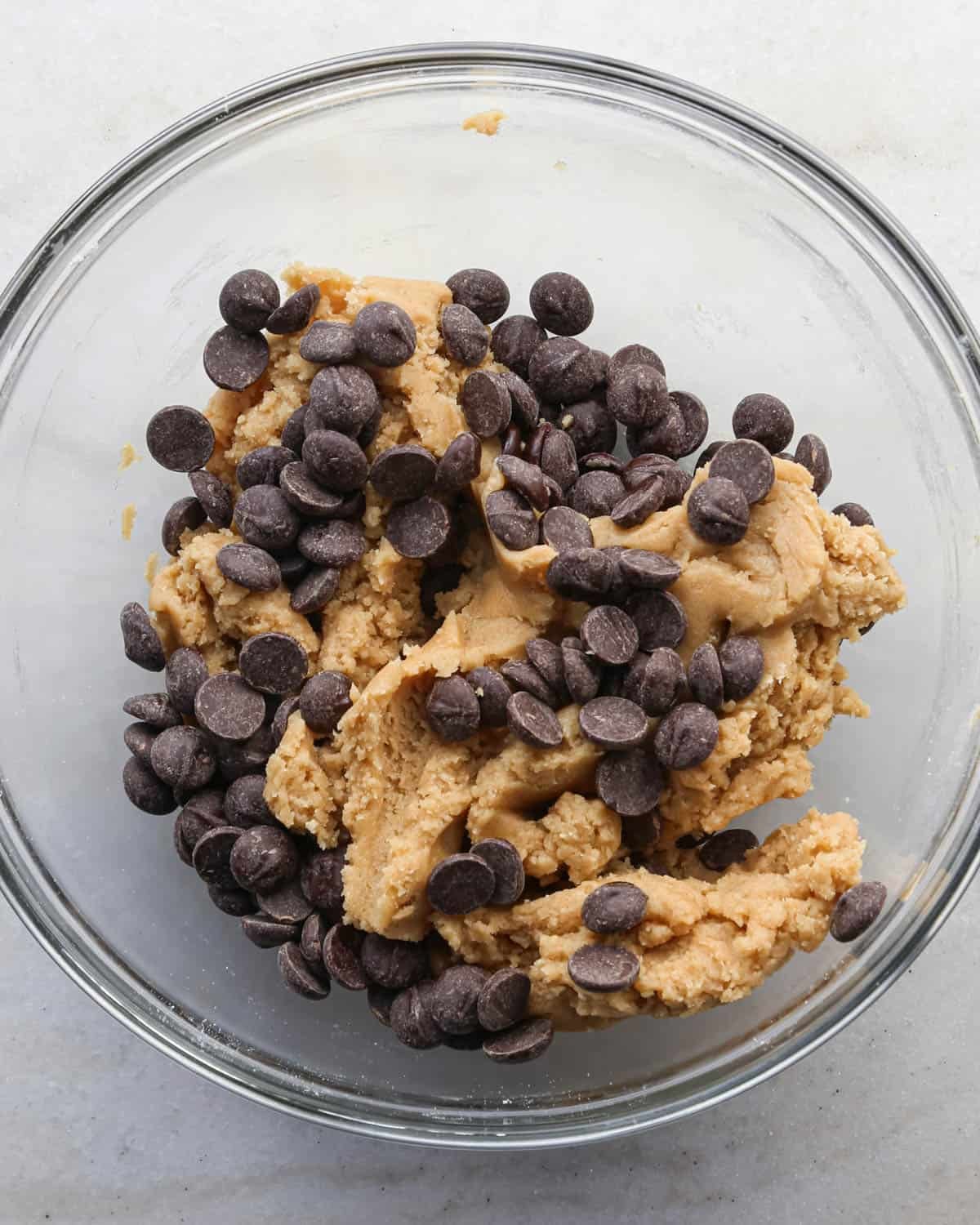 making brown butter cookie bars - chocolate chips added to the dough in a glass mixing bowl before mixing