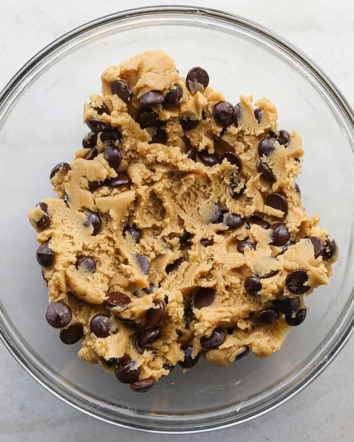 making brown butter cookie bars - dough with chocolate chips mixed in in a glass mixing bowl