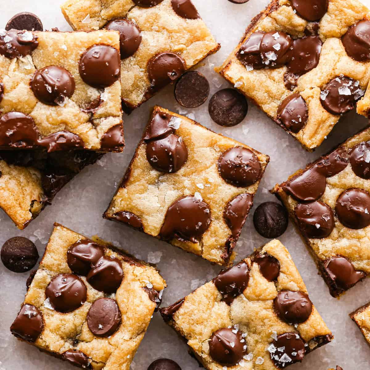 overhead photo of 8 brown butter chocolate chip cookie bars cut into squares with melty chocolate chips and topped with flaky sea salt