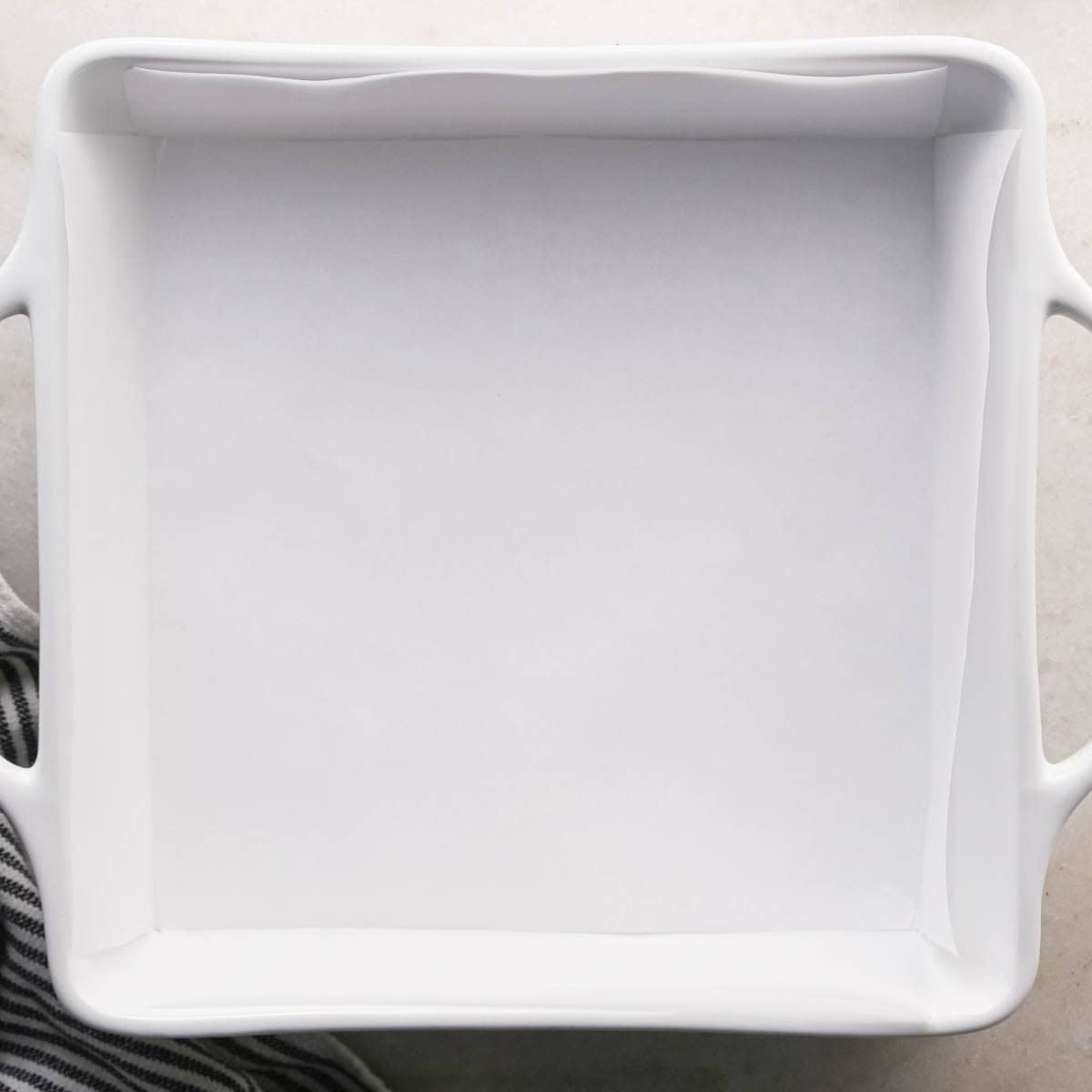 making brown butter cookie bars - white square ceramic baking dish lined with parchment paper