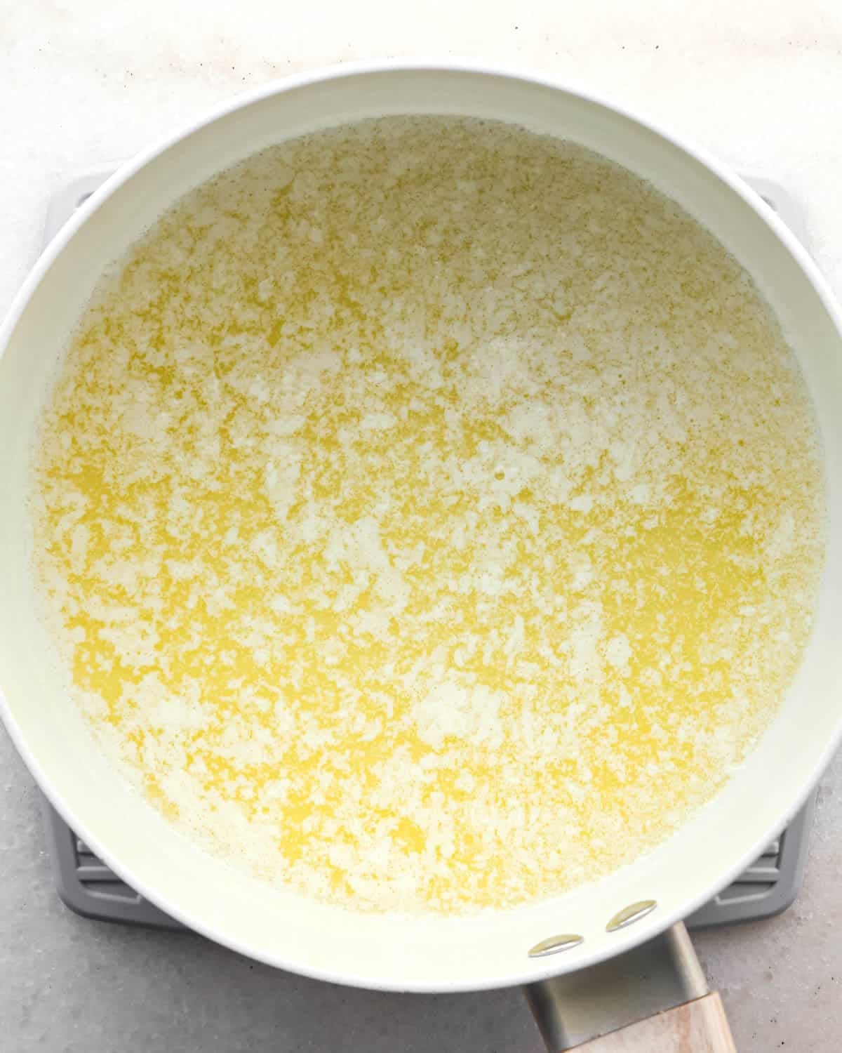making brown butter cookie bars - melted and slightly foamy butter in a white saucepan