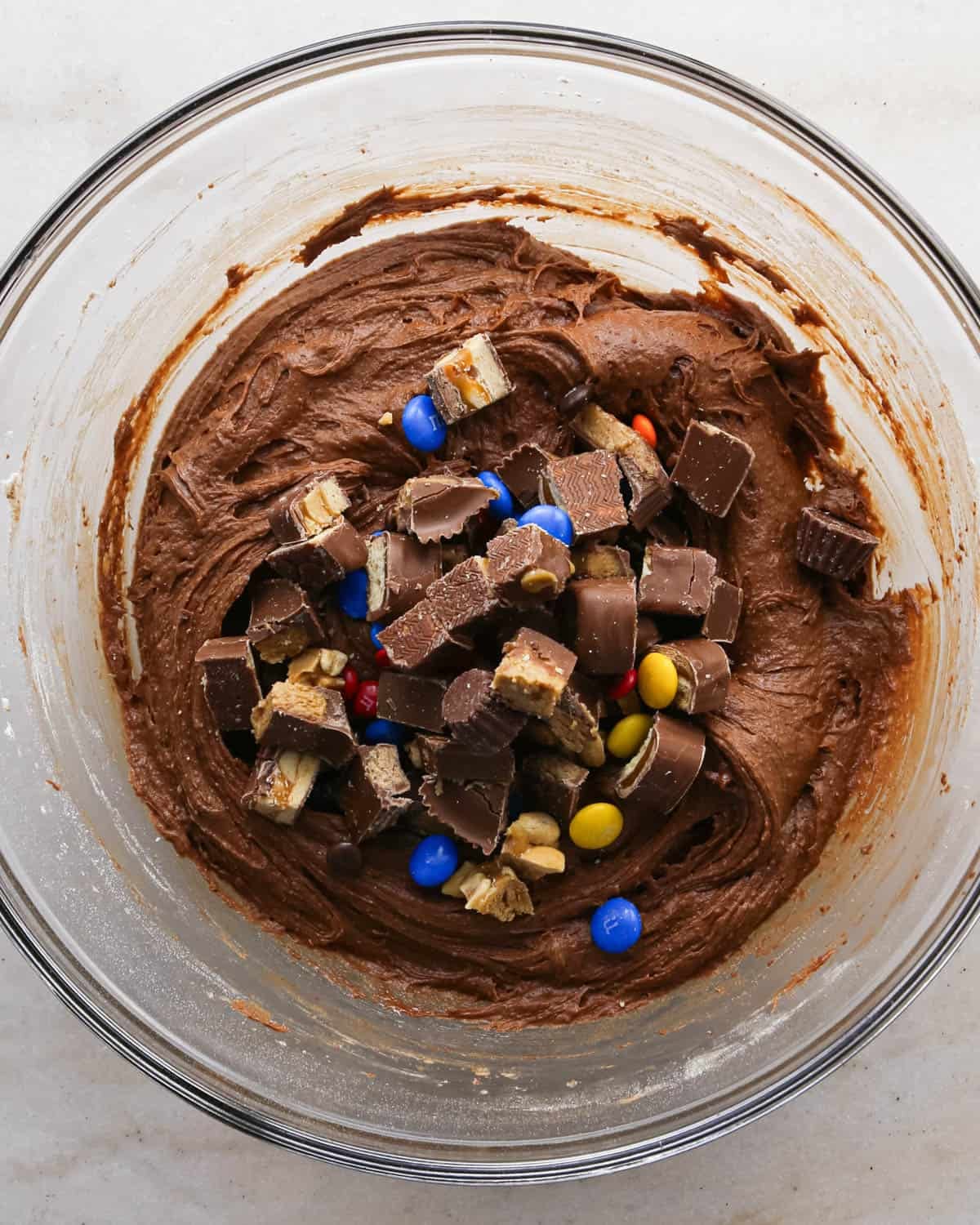 making candy halloween brownies - chopped candy added to the brownie batter in a glass mixing bowl before stirring in