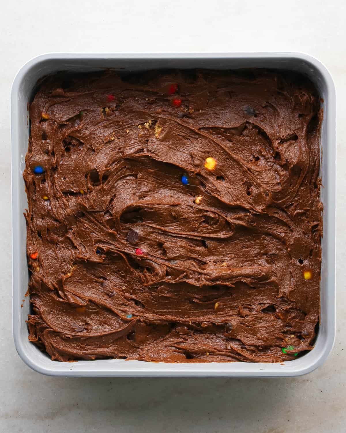 making candy halloween brownies - brownie batter spread into the white ceramic square baking dish before baking