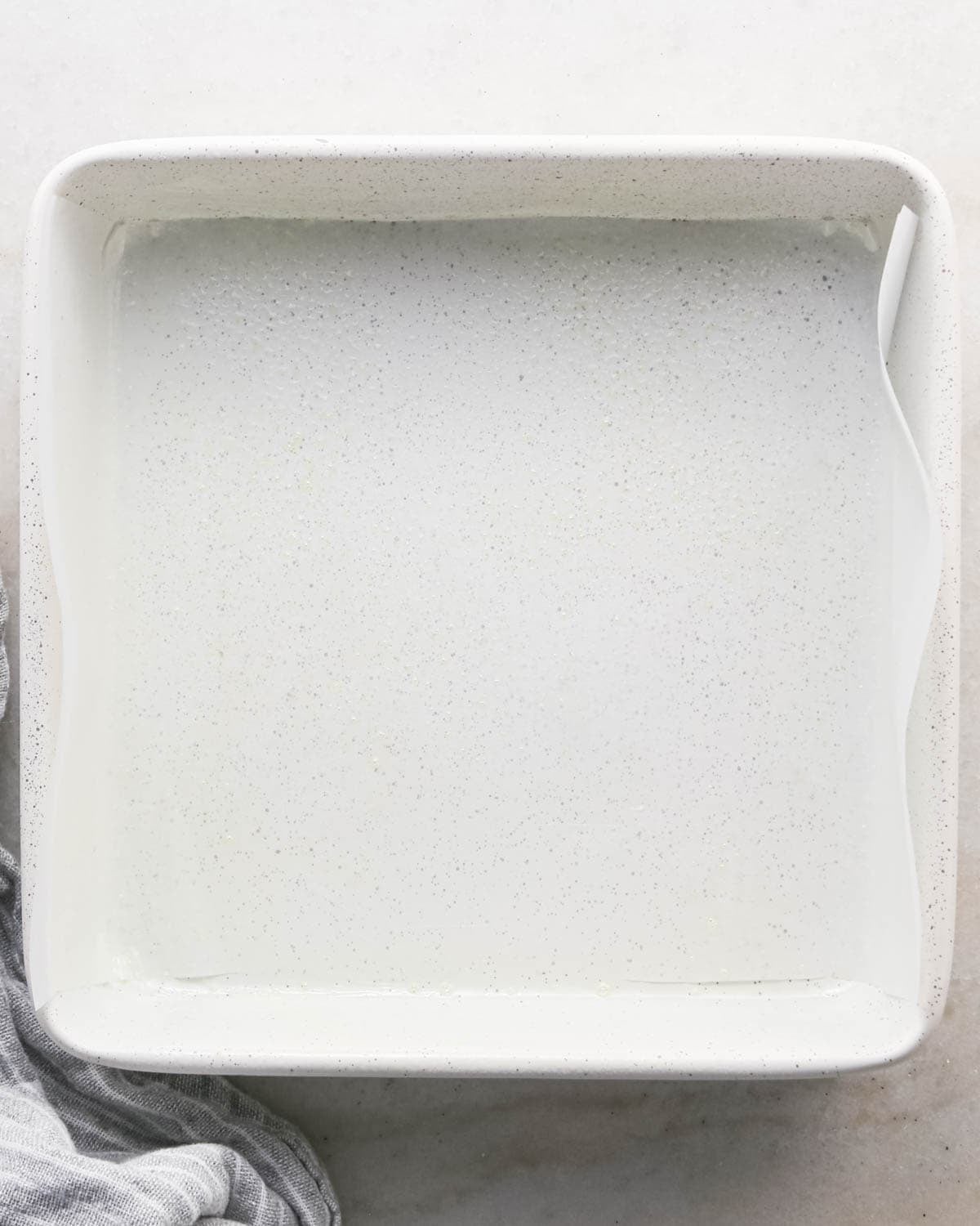 making candy halloween brownies - a white square ceramic baking dish lined with parchment paper