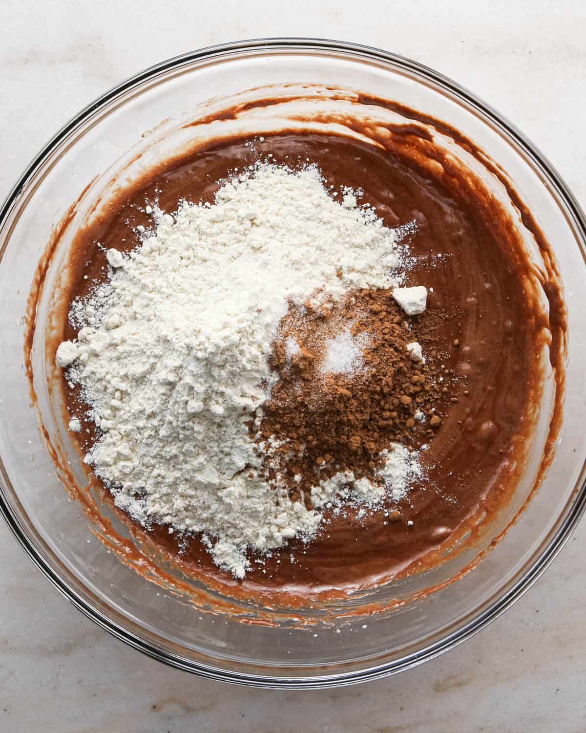 making candy halloween brownies - flour, cocoa powder and salt added to the wet ingredients in a glass mixing bowl before mixing