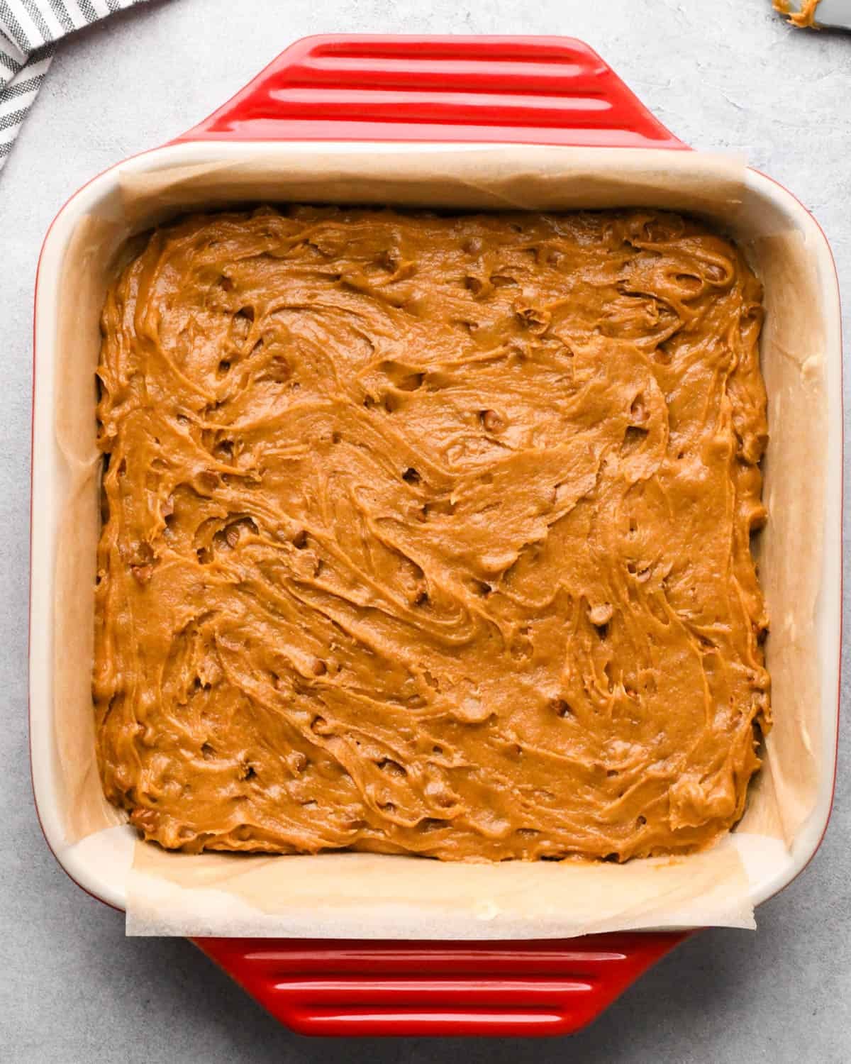 making pumpkin blondies - batter spread into a red, 9" ceramic baking dish before baking