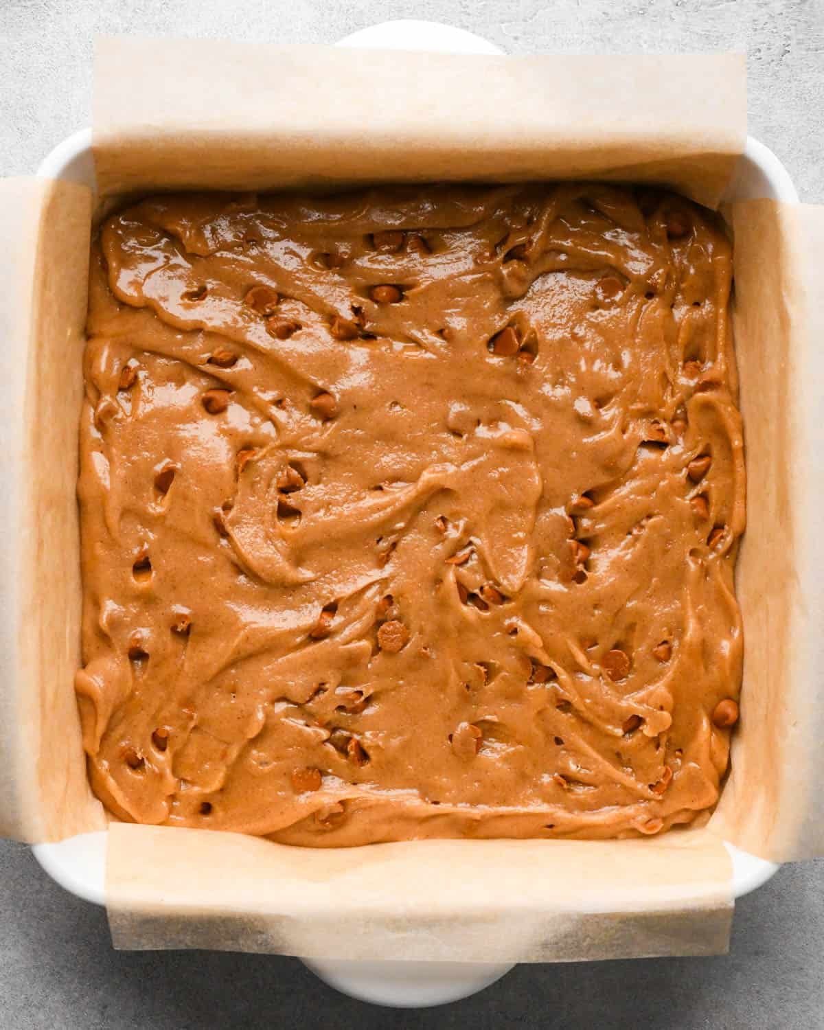 making snickerdoodle blondies - batter spread into the parchment lined baking dish