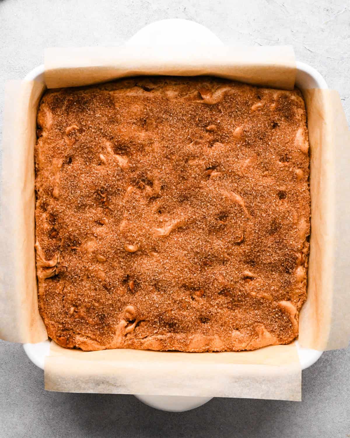 baked snickerdoodle blondies in a white ceramic, square, parchment-lined baking dish