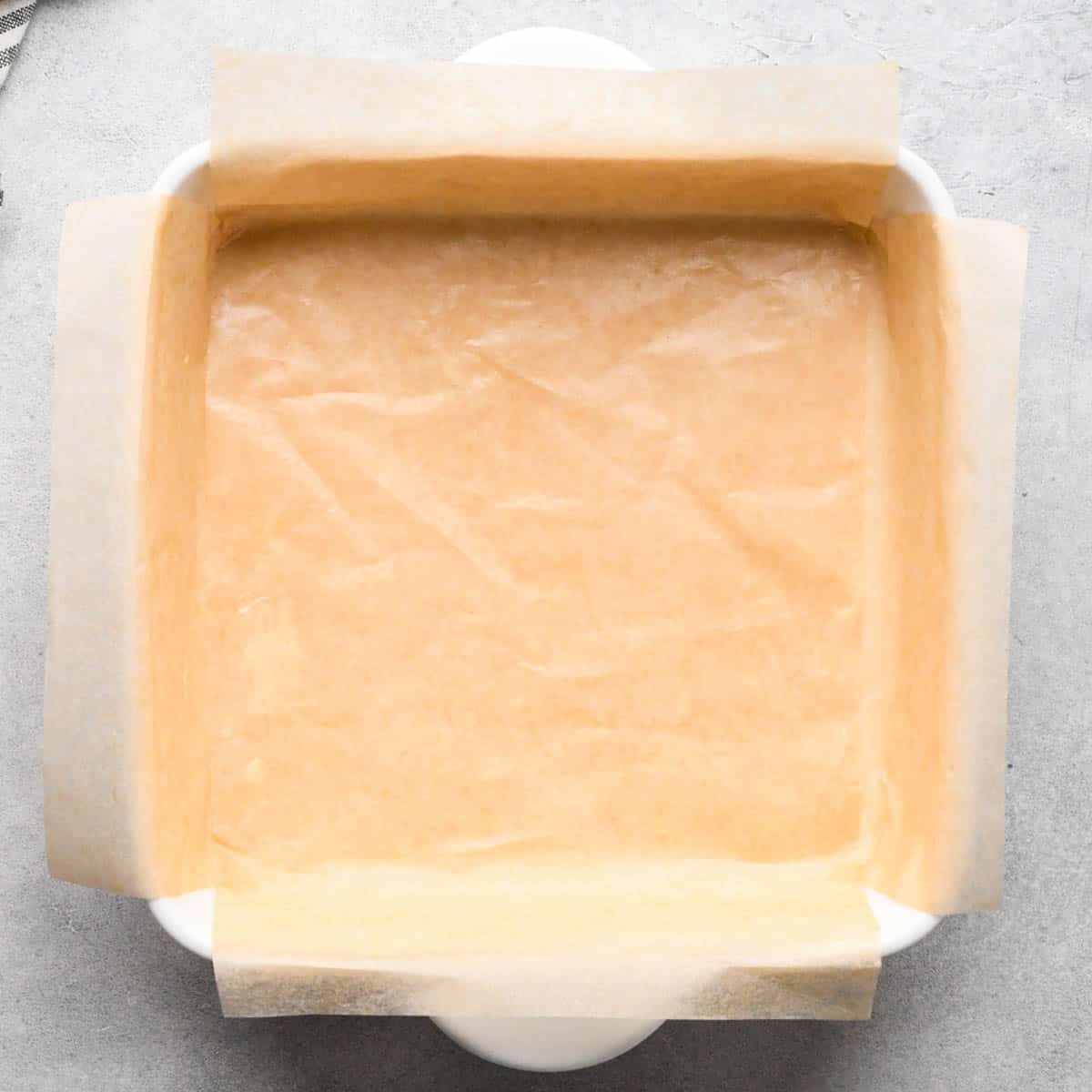 making snickerdoodle blondies - a white 8" square ceramic baking dish lined with parchment paper