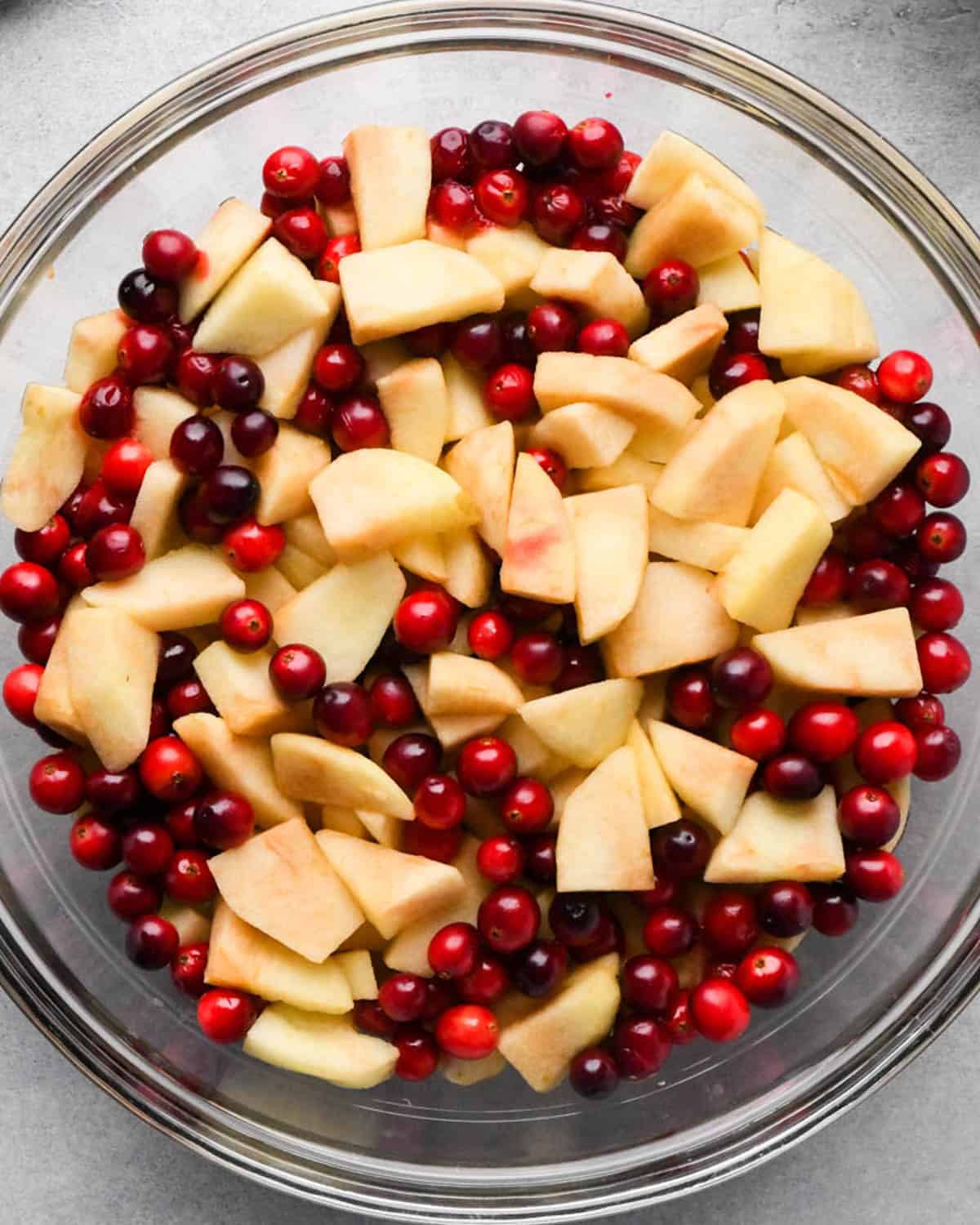making cranberry and apple pie - peeled, cored and sliced apples and cranberries in a glass bowl after being microwaved for 3 minutes