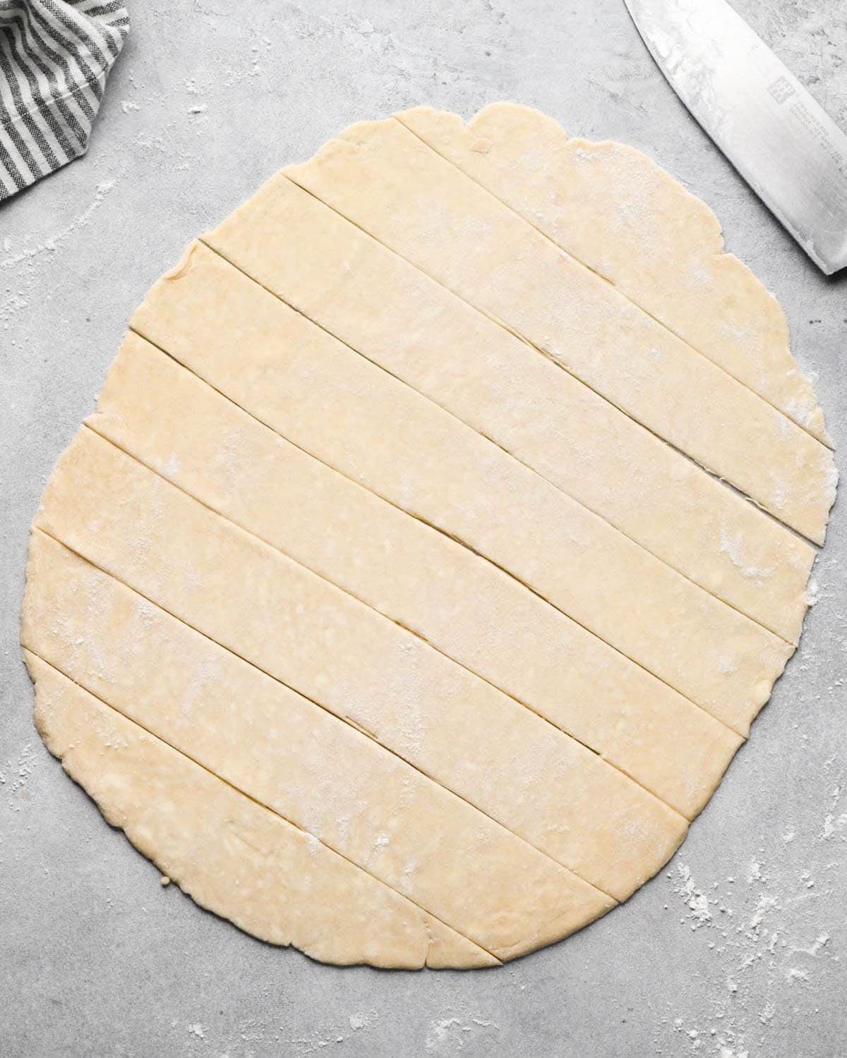 making apple cranberry pie crust - crust rolled into an oval and cut into strips