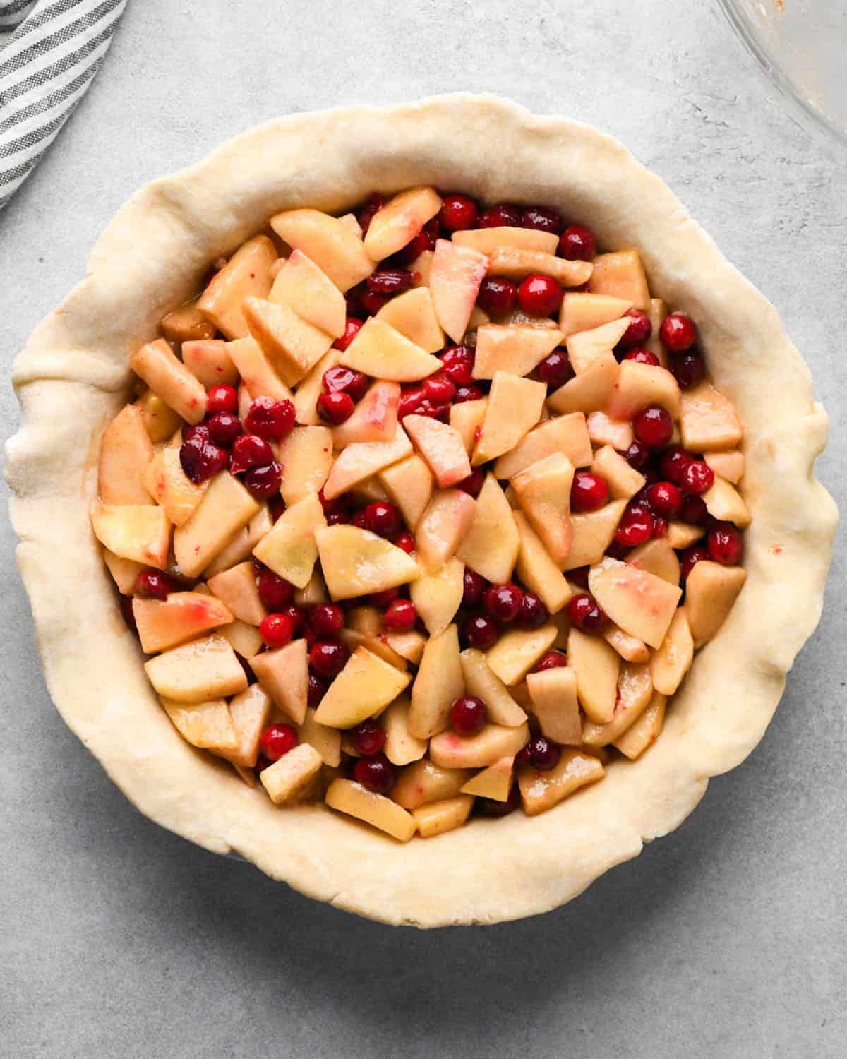 making cranberry and apple pie - filling in the bottom pie crust