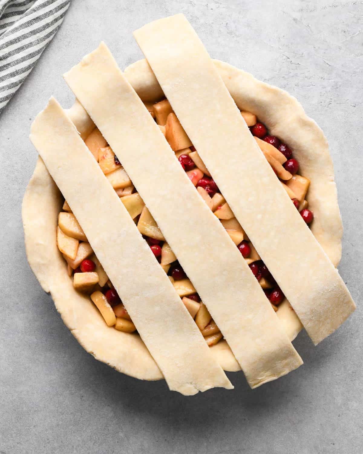 making cranberry and apple pie - forming a lattice crust over the filling