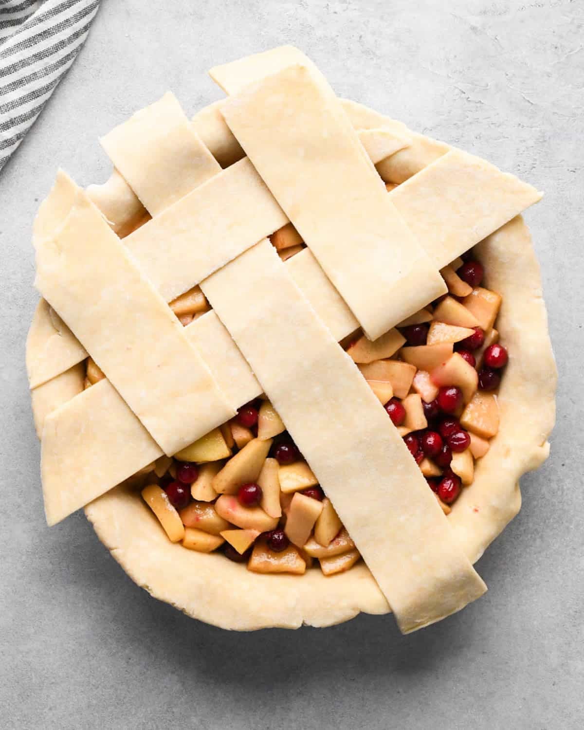 making cranberry and apple pie - forming a lattice crust over the filling