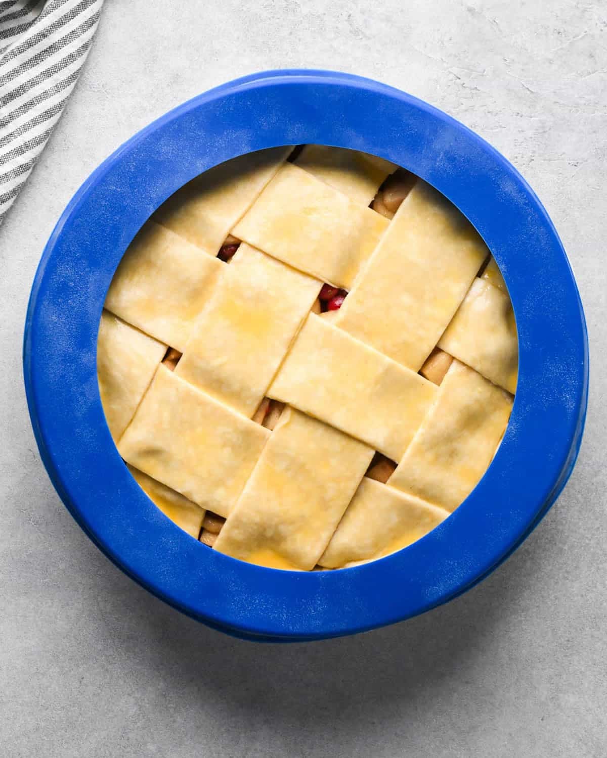 assembled apple cranberry pie with a blue pie crust shield around the outer crust before baking