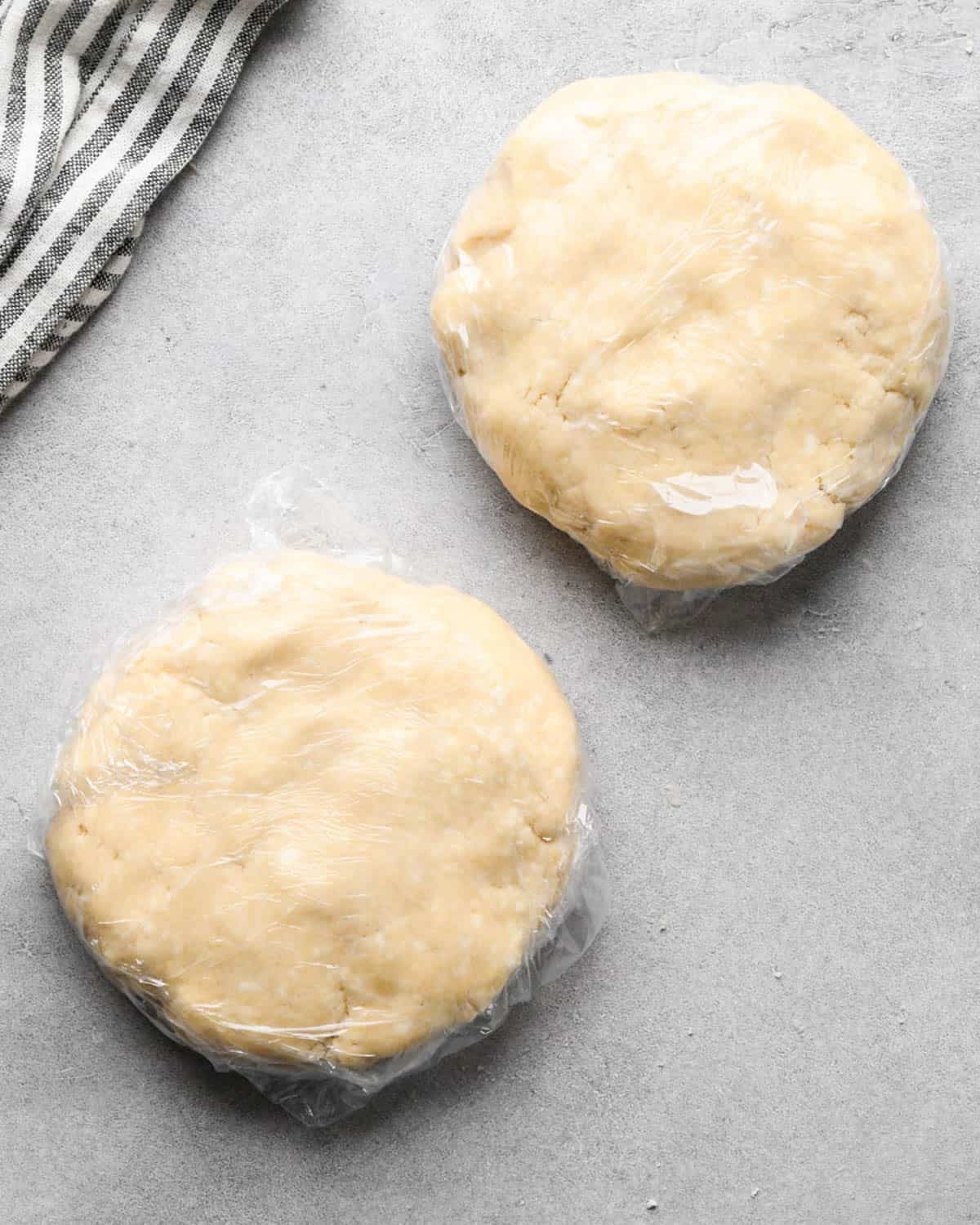 making apple cranberry pie crust - crust formed into two round discs wrapped in plastic wrap