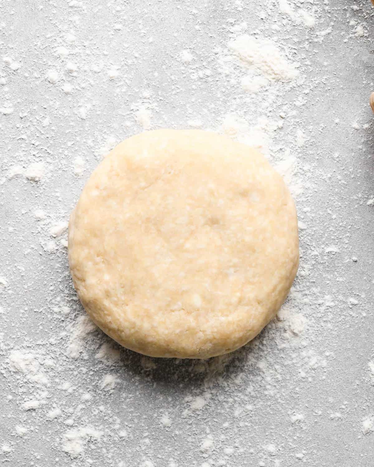 making caramel apple pie - disc of pie dough on a gray, floured surface