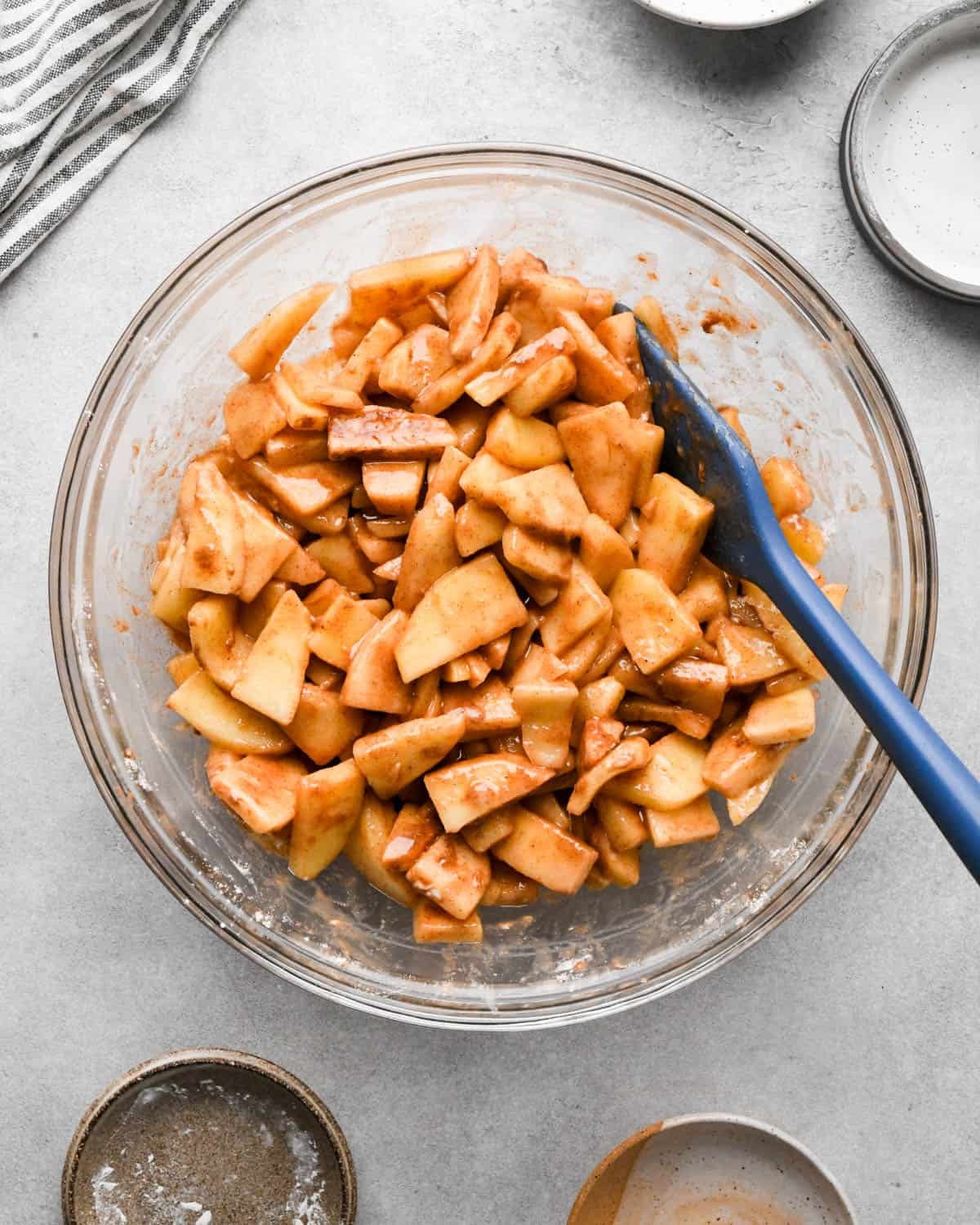 making caramel apple pie filling - apple mixture after the ingredients have been stirred into it with a blue spatula