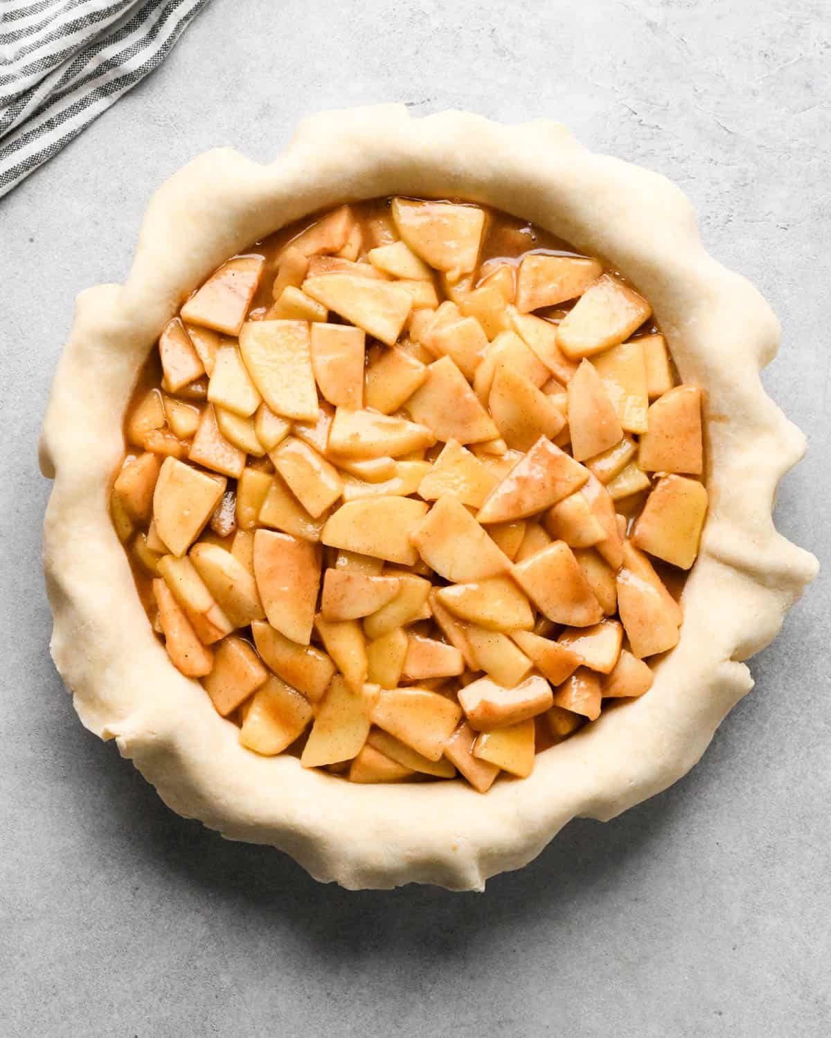 making caramel apple pie - filling put into the bottom crust in a pie dish