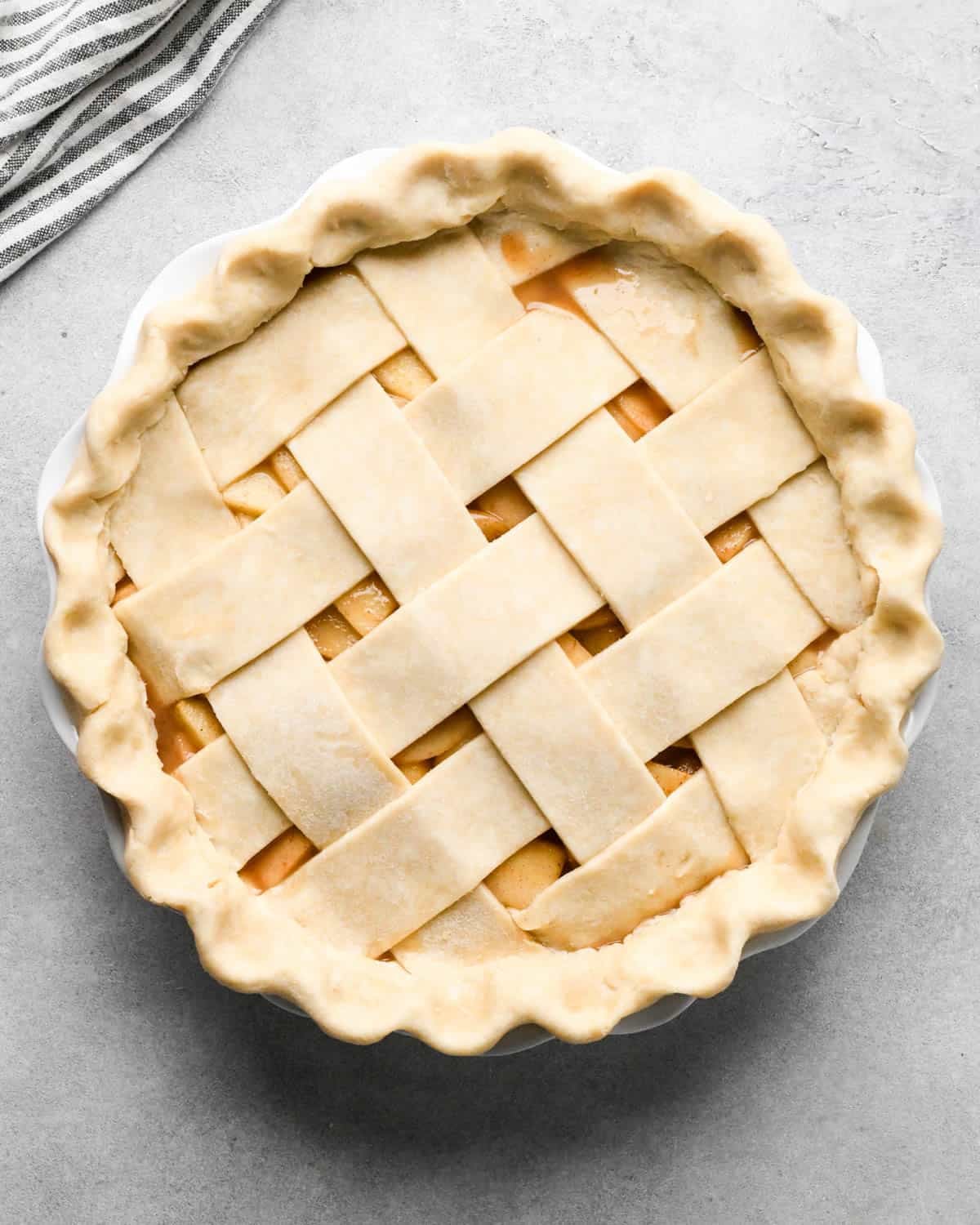 making caramel apple pie - assembled caramel apple pie in a pie dish with a lattice crust and fluted edge