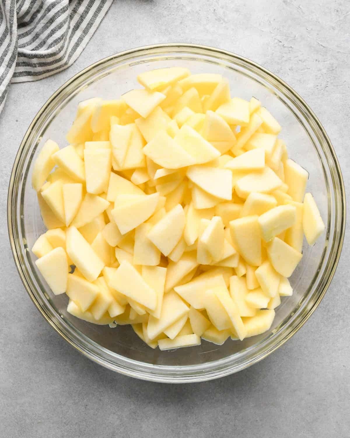 making caramel apple pie filling - peeled and sliced apples in a glass mixing bowl