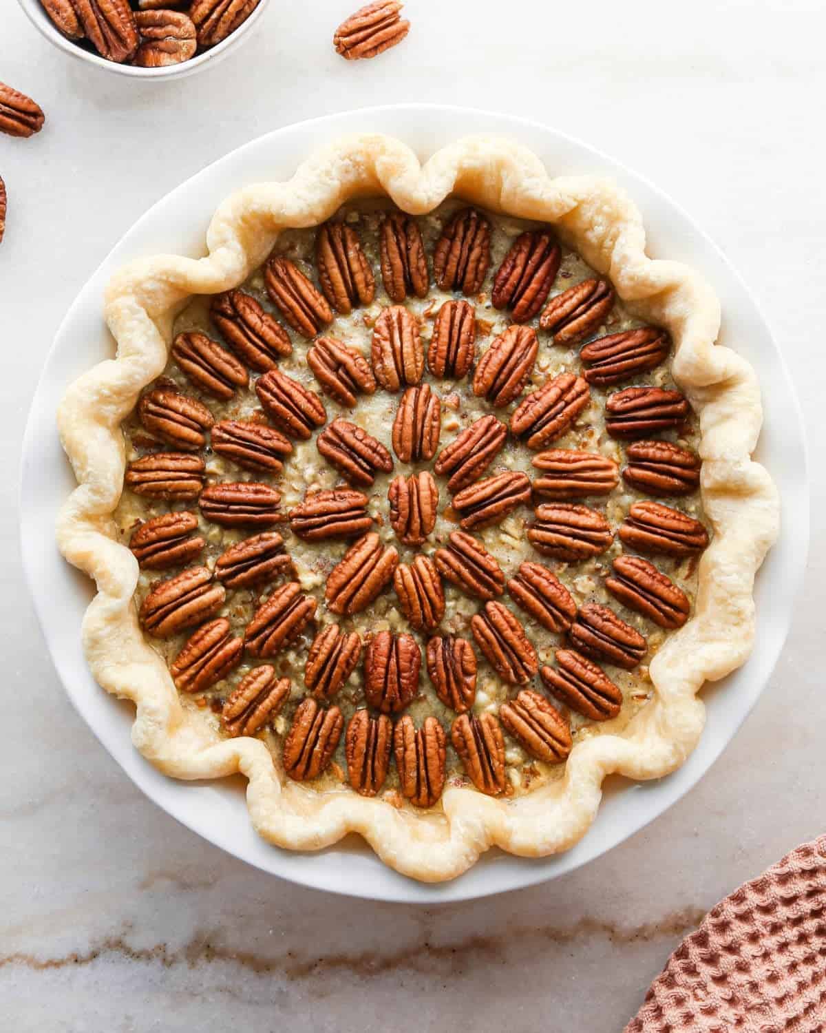 how to make pecan pie without corn syrup - final pecan pie before baking in a white ceramic pie dish