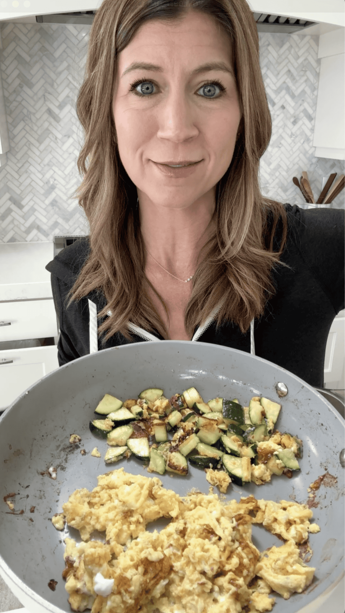 Laura from joyfoodsunshine holding cottage cheese and scrambled eggs and zucchini in a nonstick fry pan